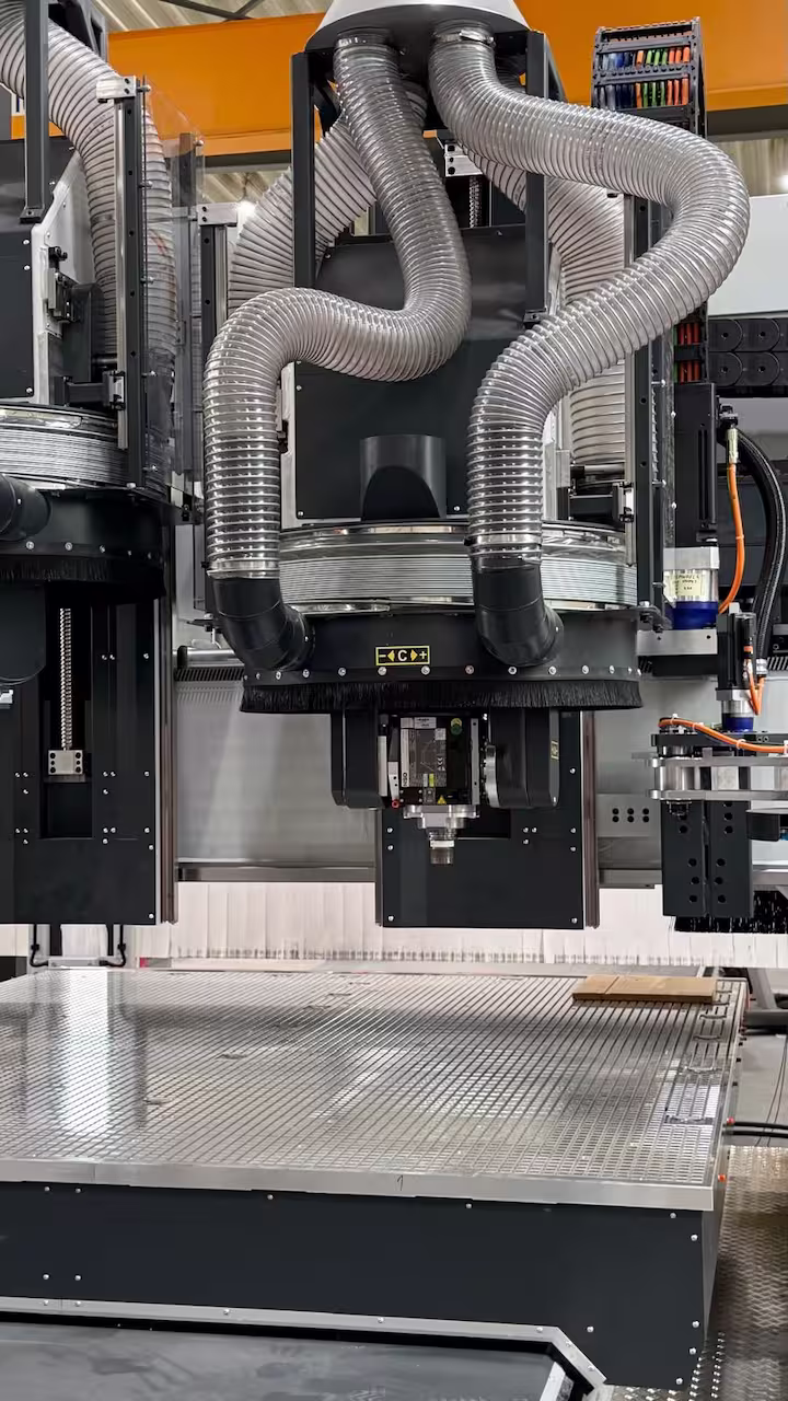 Detailaufnahme einer HSD CNC-Frässpindel mit Bürsten-Absaugkranz, flexiblen Schläuchen und Vakuumtisch im Vordergrund