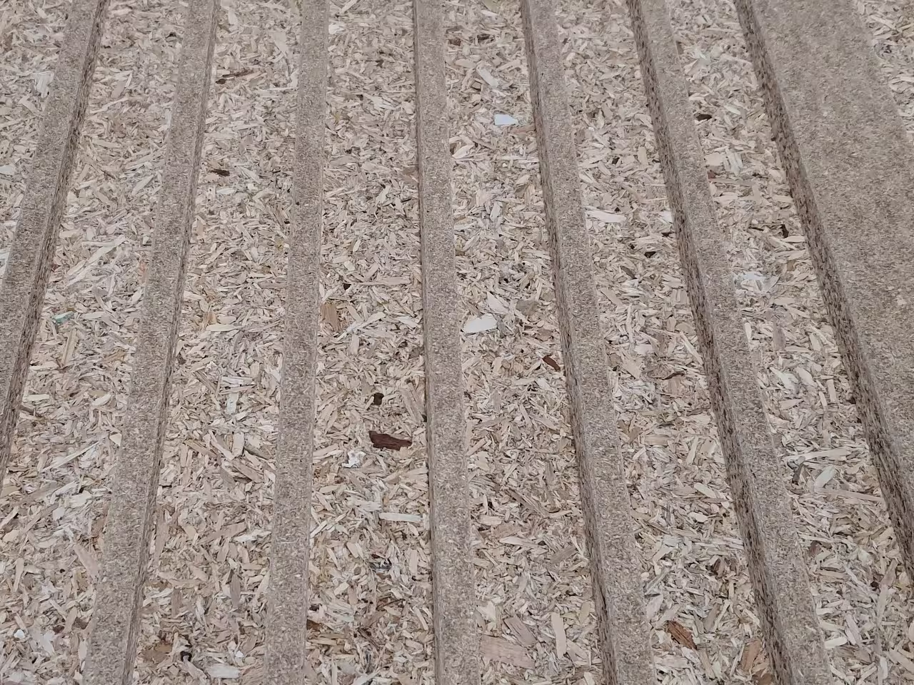 Spanplatte mit mehreren parallel eingefrästen Nuten und sichtbarer Holzspanstruktur im Plattenkern