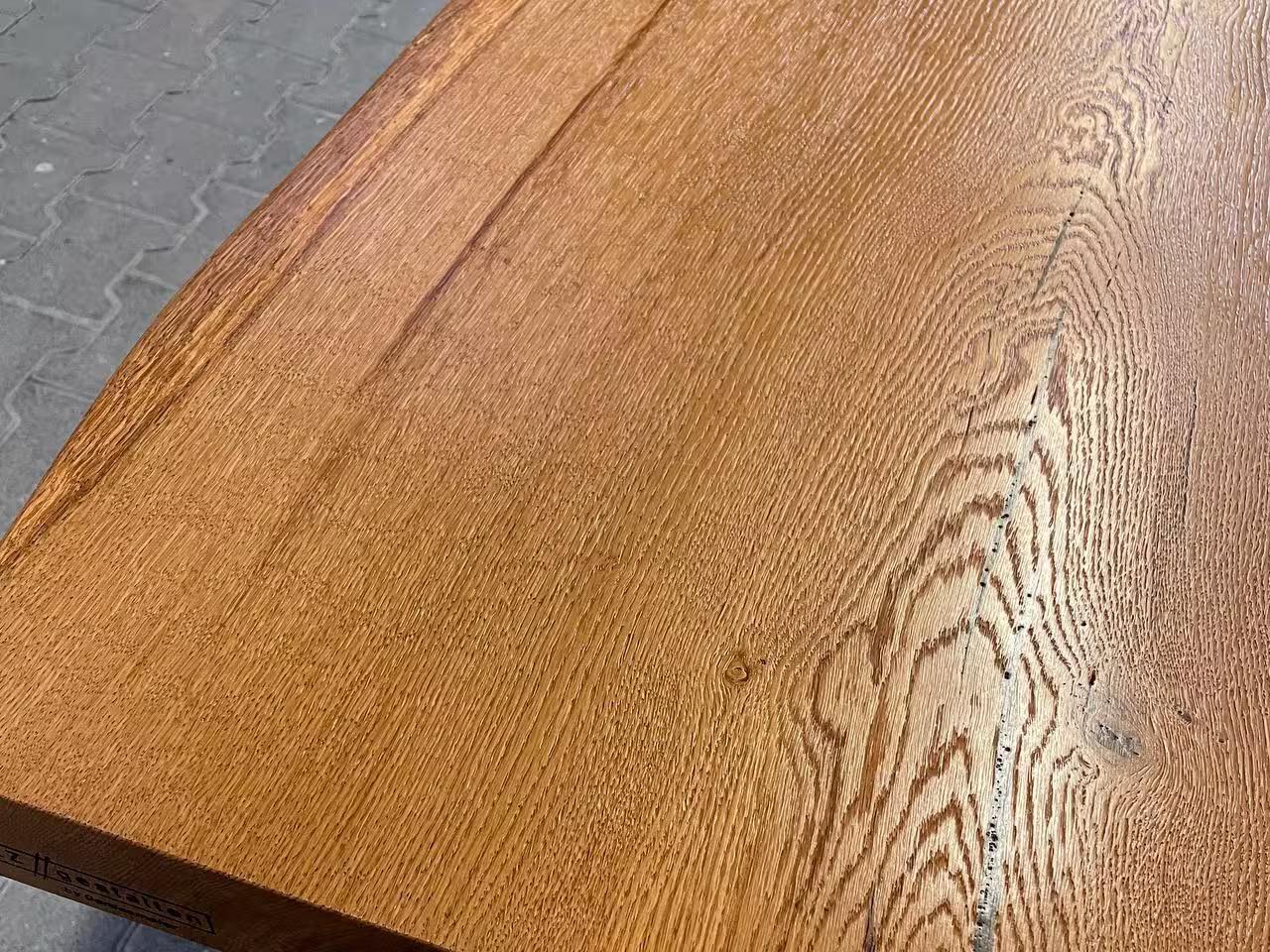 Detail einer Eichen-Tischplatte mit strukturierter Oberfläche und deutlicher Maserung.