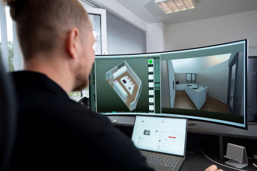 Mitarbeiter von hinten vor zwei Monitoren mit der 3D-Planung eines Raums mit Einbaumöbeln.