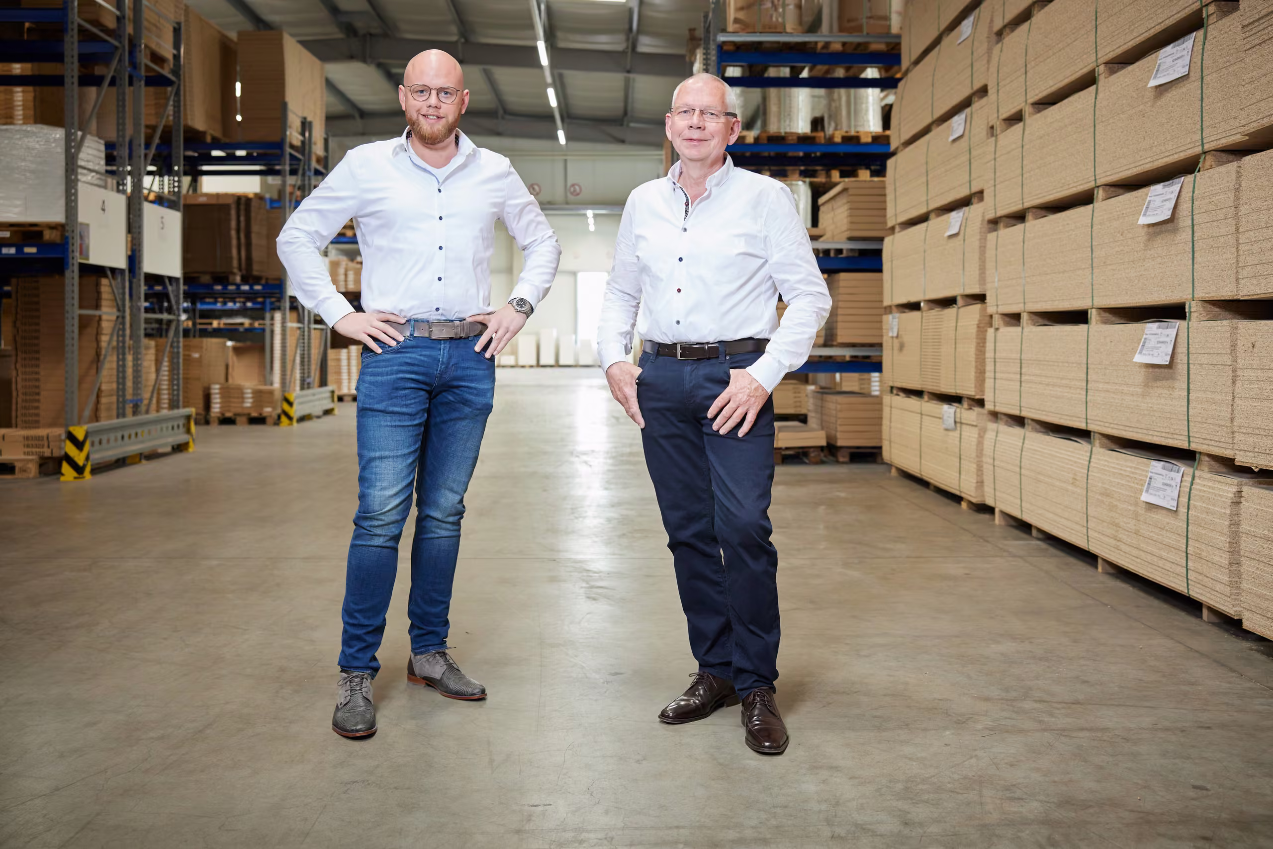Alexander und Thomas Reker stehen im Plattenlager zwischen hohen Regalen mit Platten.