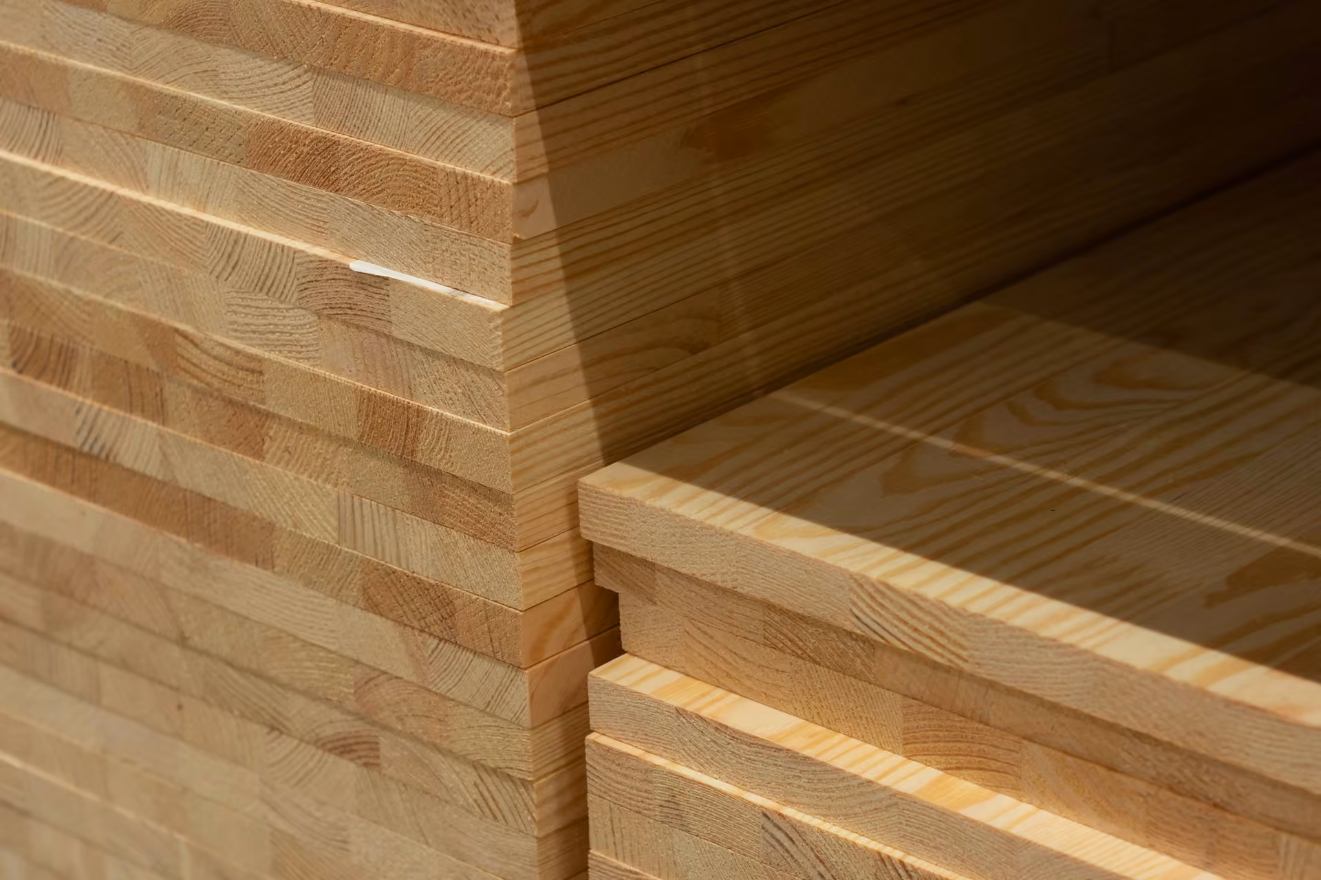 Stapel heller Leimholzplatten, an den Stirnseiten sind die miteinander verleimten Holzlamellen zu erkennen.