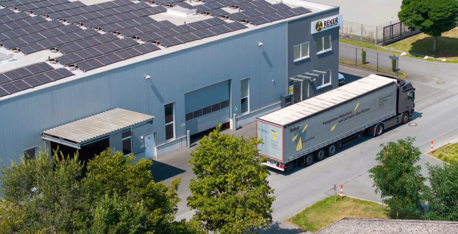 Luftaufnahme des Firmengebäudes mit Solaranlage auf dem Dach und einem LKW an der Verladerampe.