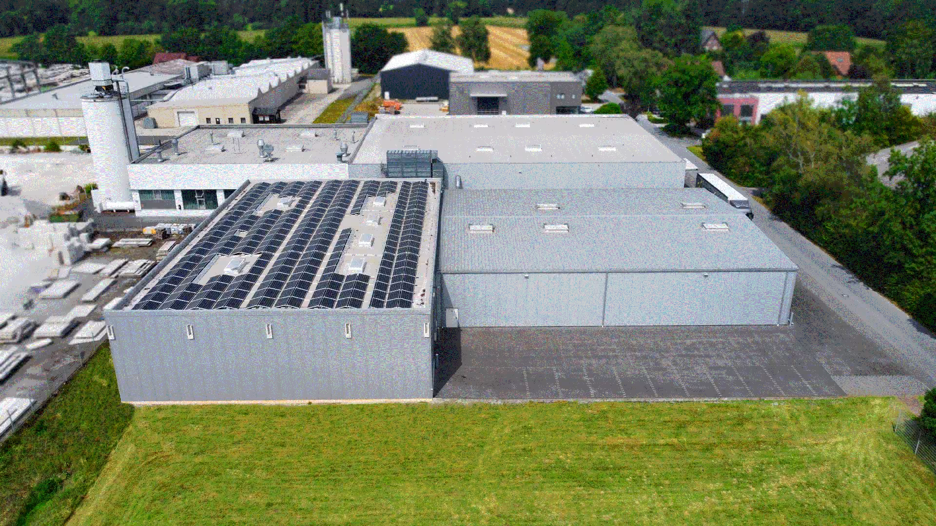 Luftaufnahme der Produktionshallen mit Solaranlage und einer großen Grünfläche im Vordergrund.
